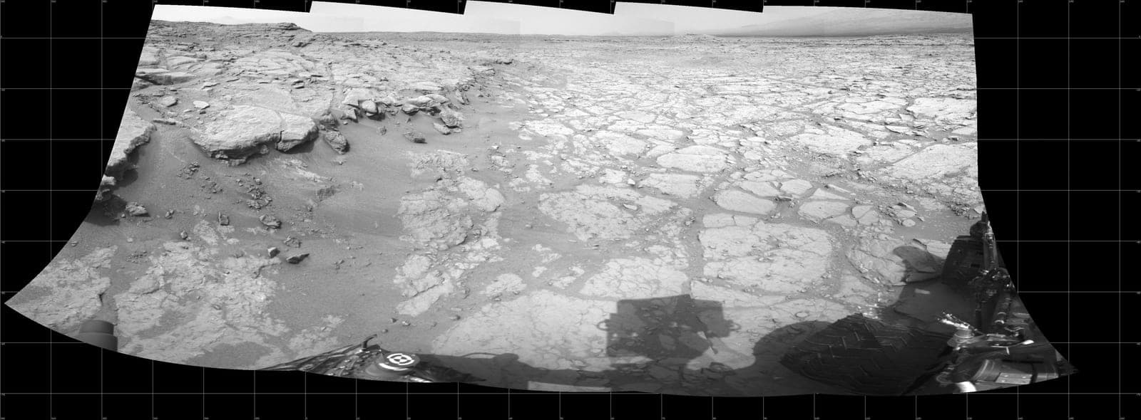 A flat, pale, finely fractured rock pavement stretching to a low horizon, photographed in black and white.
