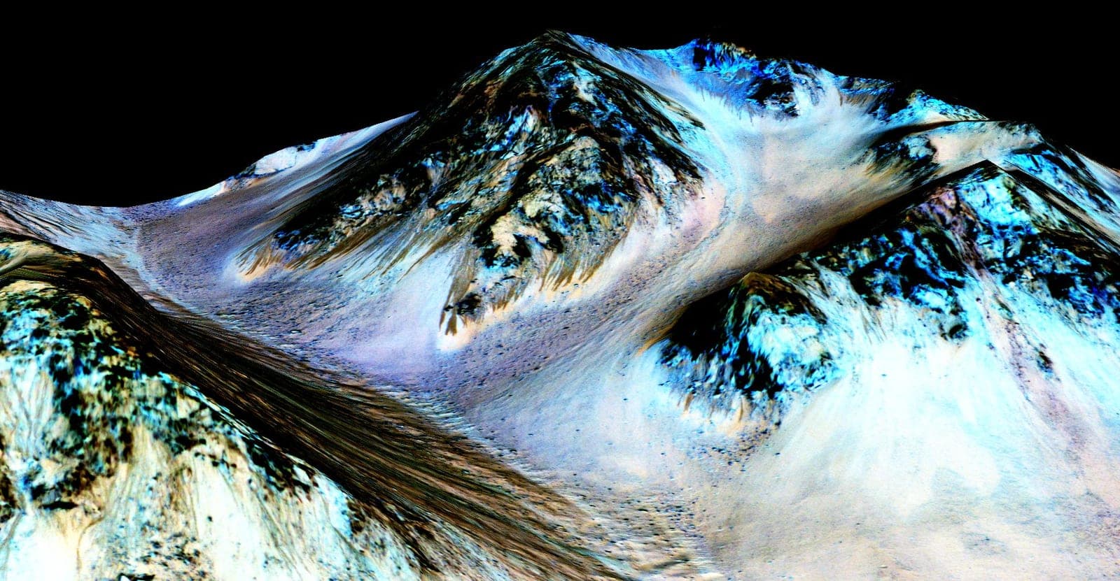 A false-colour orbital view of a steep crater slope scored by many narrow dark streaks running downhill.